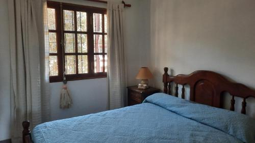 a bedroom with a bed with a blue bedspread and a window at Casa en San Lorenzo in San Lorenzo