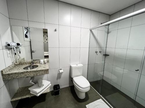 a white bathroom with a toilet and a sink at Life Hotel in Canoas