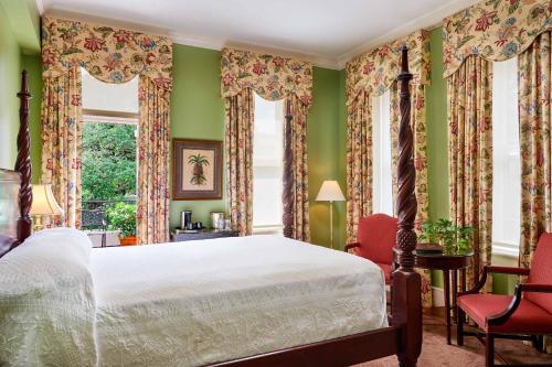 1 dormitorio con paredes verdes, 1 cama y ventanas en Planters Inn on Reynolds Square, en Savannah