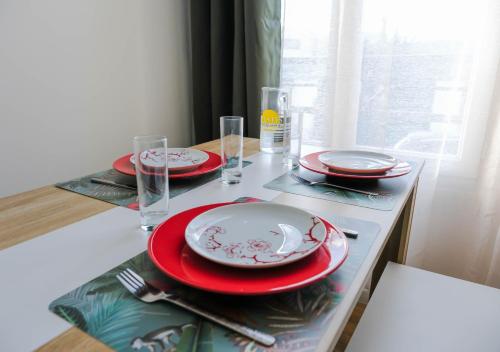 einen Tisch mit roten und weißen Tafeln und Gläsern in der Unterkunft Cosy Casa entre Paris et Disney in Neuilly-Plaisance