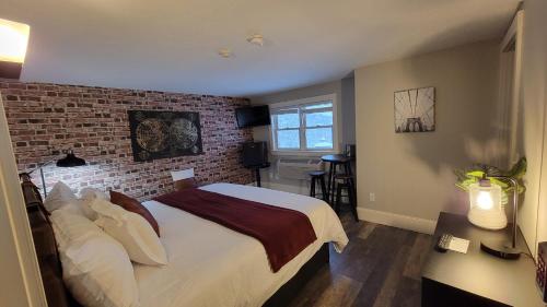 1 dormitorio con cama y pared de ladrillo en Gunstock Inn & Suites en Gilford