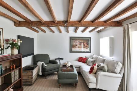 ein Wohnzimmer mit einem weißen Sofa und 2 Stühlen in der Unterkunft Two Rose Walk Cottage Cotswolds in Moreton-in-Marsh