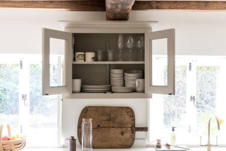 eine Küche mit einem Waschbecken und einem Schrank mit Geschirr in der Unterkunft Two Rose Walk Cottage Cotswolds in Moreton-in-Marsh