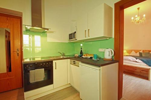 a kitchen with green walls and white cabinets at Apartment Haus Braumandl in Bad Ischl