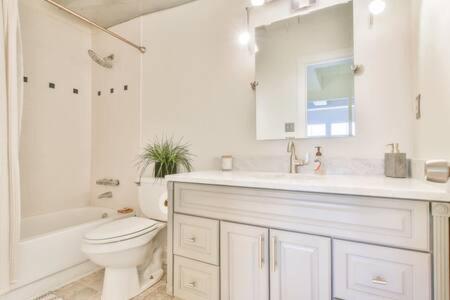 a white bathroom with a toilet and a sink at The Executive Loft - Walk to Sanford Stadium in Athens