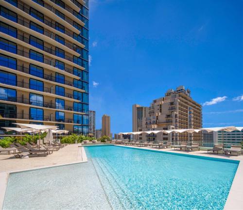 a swimming pool with chairs and buildings in the background at Sun Berry Waikiki Residence in Honolulu