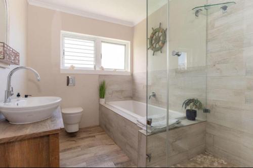 a bathroom with a tub and a sink and a shower at The Sea Soul in Cape Town