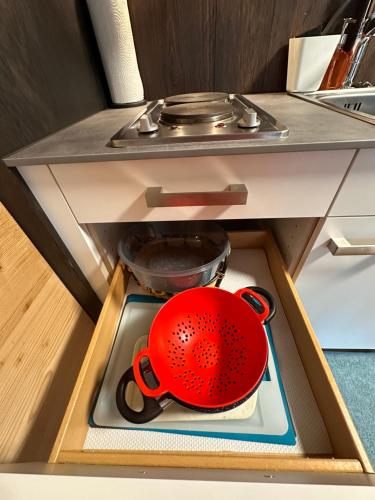 a red pot and pans in a drawer in a kitchen at One Bedroom with mountain and garden view ground floor of Chalet Solaria in Zweisimmen
