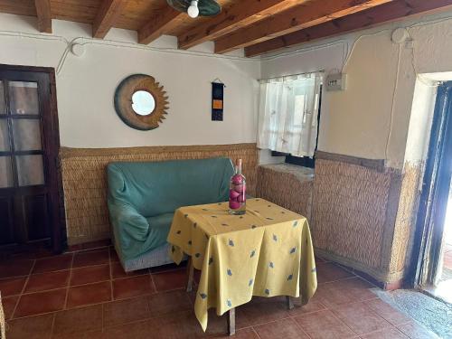 a living room with a table and a green chair at Casa Rural El Reloj in Salobralejo