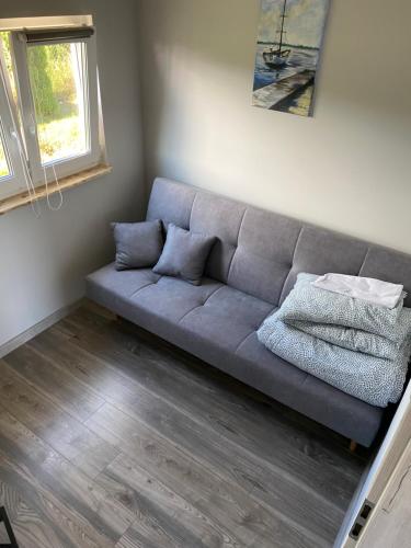 a gray couch in a living room with a window at Bajkowe Domki Marzeń Krecik in Węgorzewo