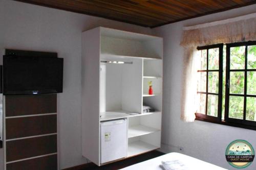 um quarto com prateleiras brancas e uma janela em Pousada Casa de Campos Guest em Campos do Jordão