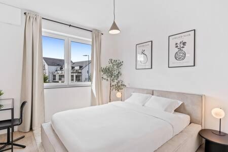 a white bedroom with a large bed and a window at Stylish Retreat in Bivange Roeser in Roeser