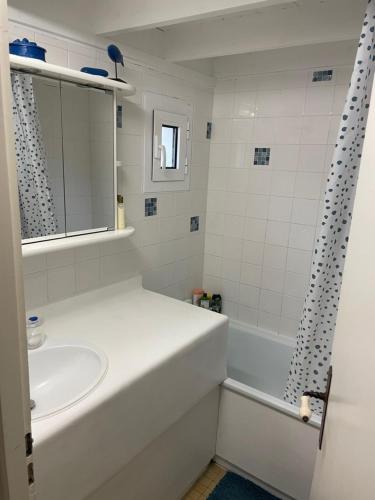 een witte badkamer met een wastafel en een bad bij Maison des rêves à 700m de la mer in Barneville-Carteret
