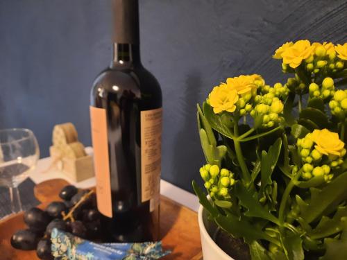 Una botella de vino sentada junto a un jarrón de flores. en Apartament Bałtycka Sardynka en Ustka