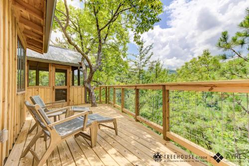 a wooden deck with two chairs and a table at The Moosewood in Treehouse Grove at Norton Creek in Gatlinburg