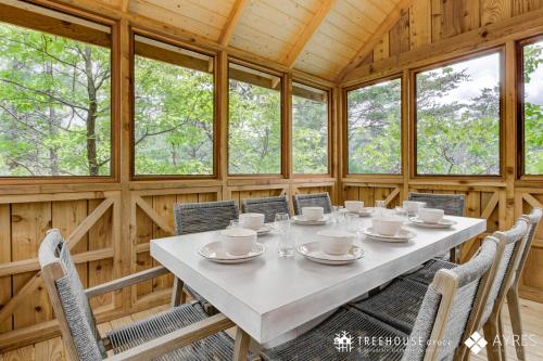 a dining room with a table and chairs and windows at The Moosewood in Treehouse Grove at Norton Creek in Gatlinburg