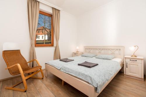 a bedroom with a bed and a chair and a window at Zala Hills Apartman - Batthyány Villapark in Zalacsány