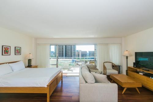 ein Schlafzimmer mit einem Bett, einem TV und einem Sofa in der Unterkunft Ilikai Tower 1228 Lagoon View 1BR in Honolulu