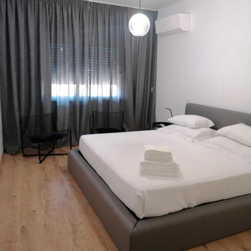 a bedroom with a large white bed and chairs at Apartamento minimalista Centenário in São Brás de Alportel