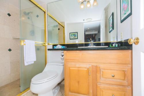 a bathroom with a toilet and a sink and a mirror at Ilikai Tower 1228 Lagoon View 1BR in Honolulu
