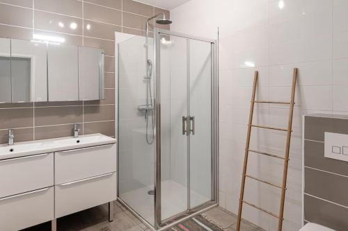 ein Badezimmer mit Glasdusche und Waschbecken in der Unterkunft La villa des mouettes in Biscarrosse