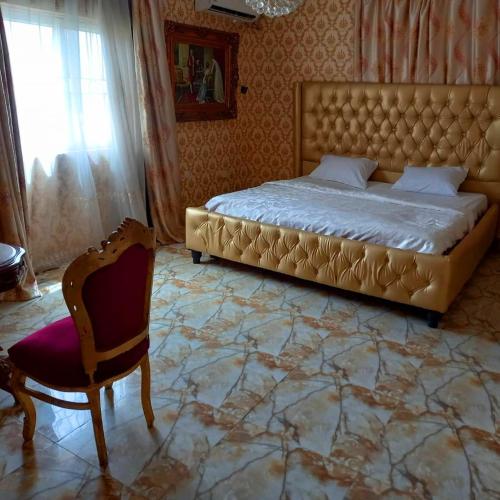 1 dormitorio con 1 cama extragrande y 1 silla en Grand Emperor Museum Hotels and Resorts, en Lekki