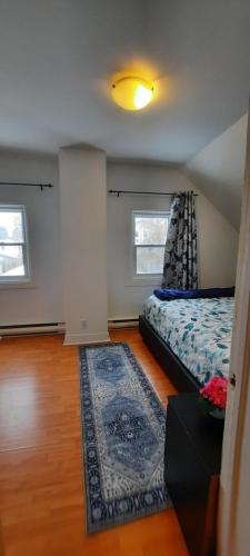 a bedroom with a bed and a rug and two windows at Le 111 Henri in Gatineau