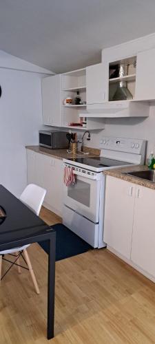 a kitchen with white cabinets and a sink and a stove at Le 111 Henri in Gatineau