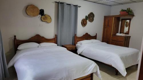 2 camas en una habitación con sábanas blancas en cabanas las molas, en Volcán