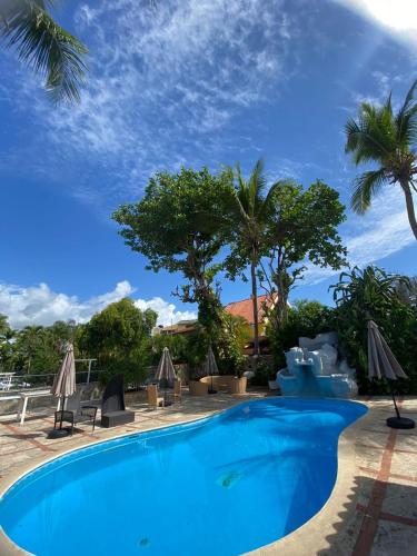 una piscina en un complejo con palmeras y sombrillas en D' Franchesis Hostal en Juan Dolio