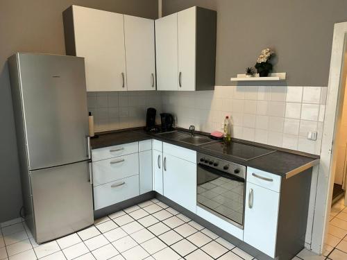 cocina con armarios blancos y nevera de acero inoxidable en Gemütliche Zimmer - Messe Gruga, en Essen