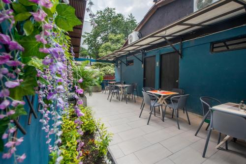 d'une terrasse avec des tables, des chaises et des fleurs violettes. dans l'établissement HOTEL BALI AT POBLADO, à Medellín