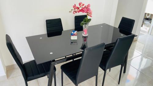 a dining room table with black chairs and a vase with flowers at Apartamento/Departamento independiente nuevo in Tacna