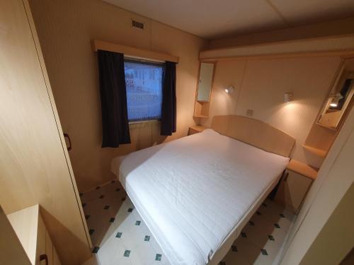 Habitación pequeña con cama y ventana en Camping du Lac MH Azur, en Égletons