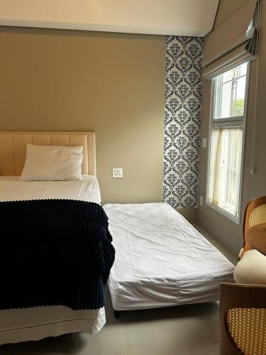 a bedroom with two beds and a window at Vilinha típica - Suíte Onze Tuin - Entrada com senha - Somos hospedagem por temporada in Holambra
