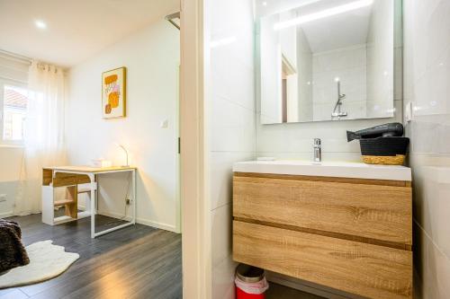 ein Bad mit einem Waschbecken und einem Spiegel in der Unterkunft Le Charles in Montbéliard