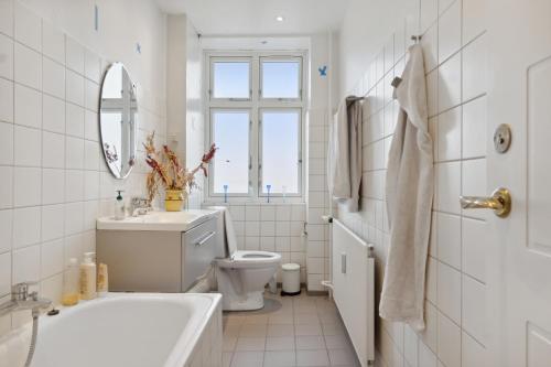 a white bathroom with a sink toilet and a mirror at Hyggelig & Lys Lejlighed med plads til 4 nær Zoo in Copenhagen