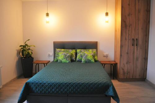 Schlafzimmer mit einem Bett mit grüner Bettwäsche und Kissen in der Unterkunft Apartament Aleksandra in Tolkmicko