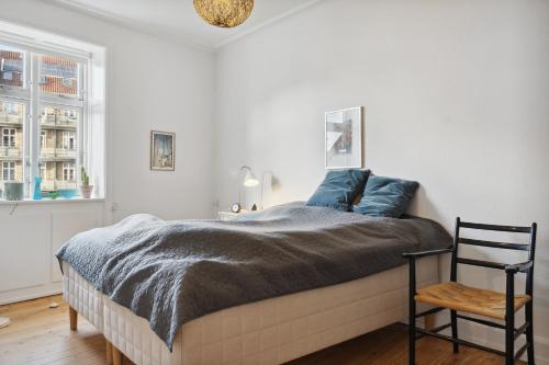 Un dormitorio con una cama con almohadas azules y una silla en Hyggelig & Lys Lejlighed med plads til 4 nær Zoo, en Copenhague