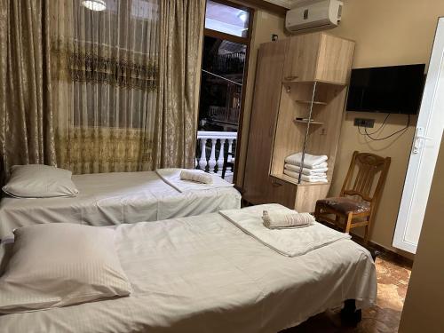 a room with two beds and a television and a window at Linda Guest house in Batumi