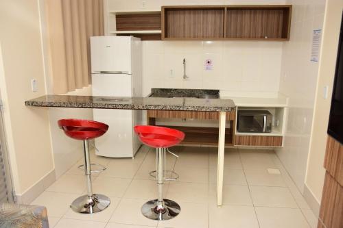 una cocina con 2 taburetes rojos y una barra en Reserve Caldas Lacqua 3, en Caldas Novas