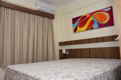 1 dormitorio con 1 cama con una pintura en la pared en Reserve Caldas Lacqua 3, en Caldas Novas