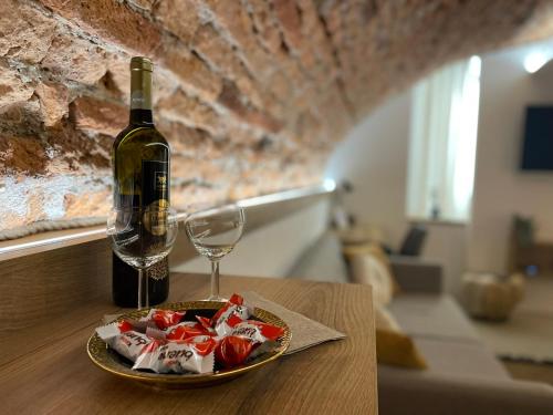 a bottle of wine and a plate of candy and a wine glass at UnderStreet studio with private parking in Košice