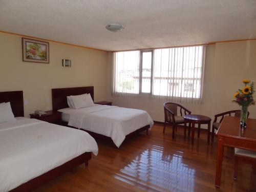 a hotel room with two beds and a desk at Hotel Lottus in Quito