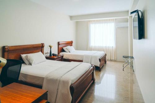 a hotel room with two beds and a window at Hotel Marcelius in Guayaquil