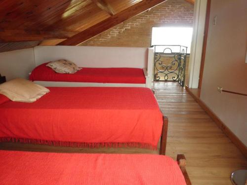 a bedroom with two red beds and a staircase at El Calden in Villa Ciudad de America