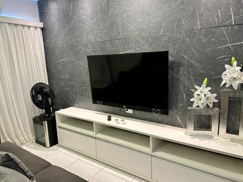 a living room with a tv on a white entertainment center at Muro Alto Clube Residence in Ipojuca