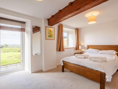 um quarto com uma cama grande e uma janela grande em 5 Bed in Widemouth Bay 89900 em Week Saint Mary