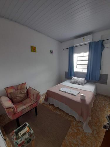 a bedroom with a bed and a chair and a window at Hotel Perola Ltda in Cuiabá