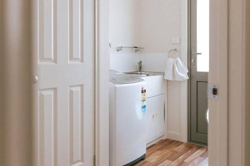 cocina blanca con fregadero y lavadora en Mara House - Space for Everyone, en St Helens